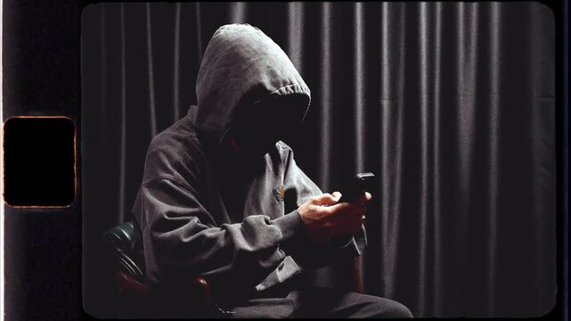 Anonymous hooded hacker using a smartphone