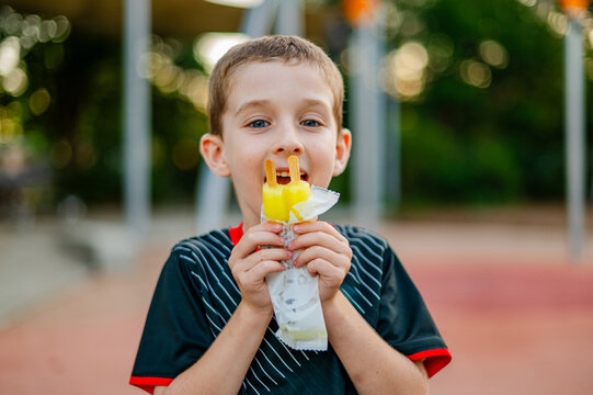 A child holding a icy pole, smiling and enjoying his treat