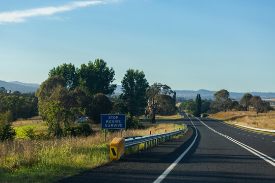 Stop revive survive sign beside highway road through Australian countryside landscape