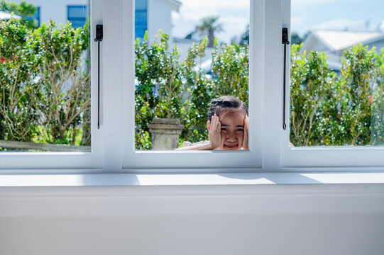 Young Samoan girl looking through glass windows from the outside on sunny day