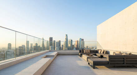 Obraz premium A modern rooftop patio with a sectional sofa and fire pit overlooks the Los Angeles skyline at sunset.