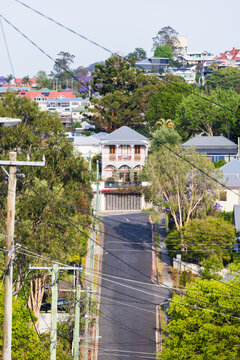 Treelined steep residential street climbing uphill viewed from elevated viewpoint