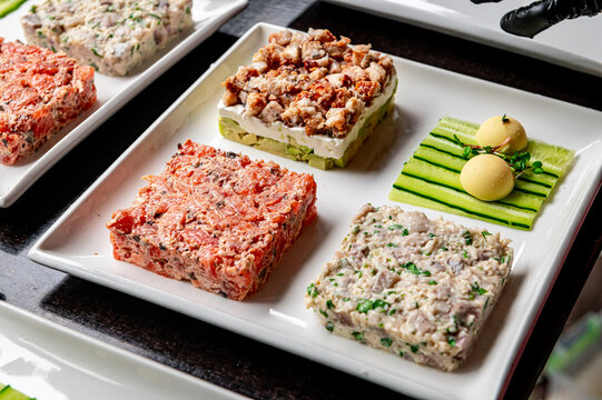 Culinary display of prepared dishes on a white plate in a restaurant. Four different food items are arranged on a plate in a restaurant setting.