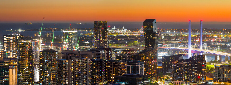 Aerial panorama view of lights of a city skyline with rooftop cranes and a bridge