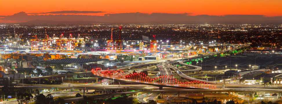 Aerial panorama view city lights at twilight over freeways and waterfront docks