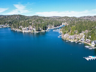 Drone view of a mountain lake surrounded by pine forest and waterfront houses with docks and marina. Suitable for travel, real estate, and outdoor lifestyle themes. © A