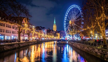 Fototapeta premium Nighttime festive canal scene with illuminated Ferris wheel and glowing city lights reflecting on water decorated with autumn trees and European architecture