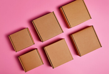 Fototapeta premium Six brown cardboard shipping boxes are neatly arranged on a vibrant pink background