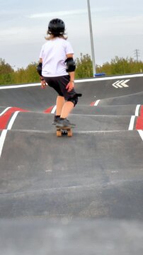 child skateboarding on pumptrack track, young boy with safety gear riding skateboard, active lifestyle and outdoor sports for kids.