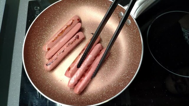Cooking sausages in a pan, close-up view showing sizzling heat