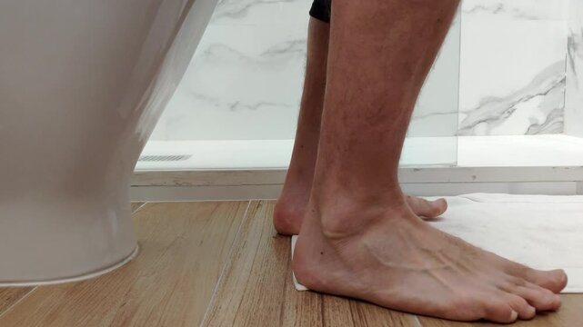 Man sitting and rising from toilet, intimate daily routine, home bathroom