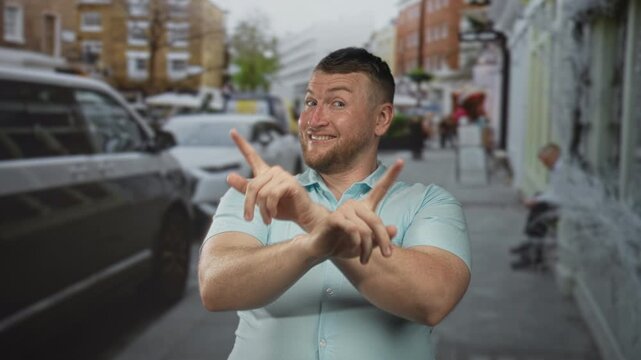 Man showing hands up and crossed fingers in a stop gesture on a busy city street near parked cars; firm rejection.