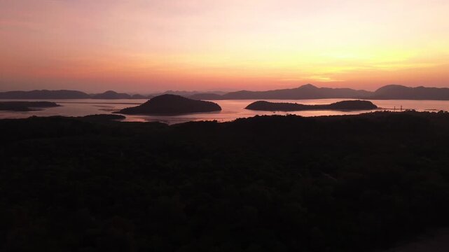 Minimal aerial view of tropical sunset horizon with island group silhouettes and mountains in background, calm sea Koh Jum Thailand ideal for meditation relaxation background and mindfulness content