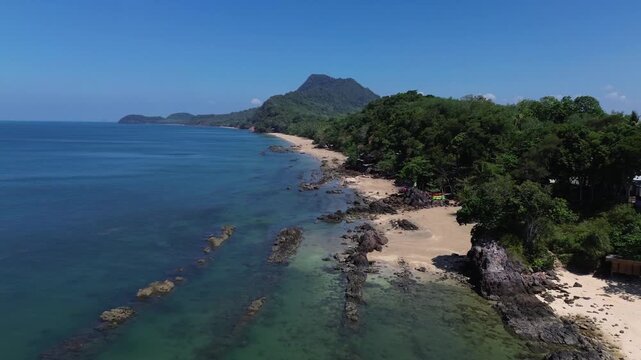 Aerial view of long tropical shoreline on Koh Jum Thailand with mountains in background clear turquoise water and natural coastline creating scenic remote island landscape in Southeast Asia