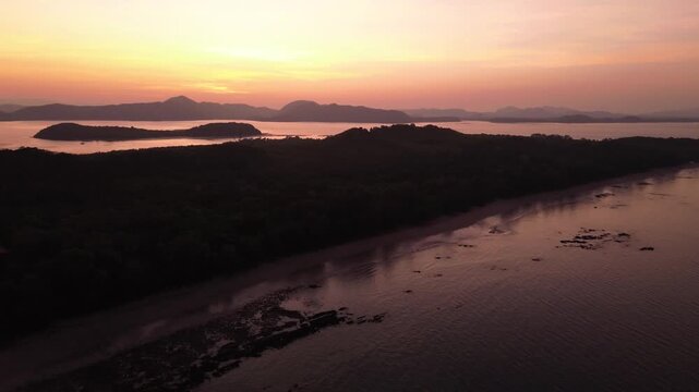Minimal aerial view of tropical sunset horizon with island group silhouettes and mountains in background, calm sea Koh Jum Thailand ideal for meditation relaxation background and mindfulness content