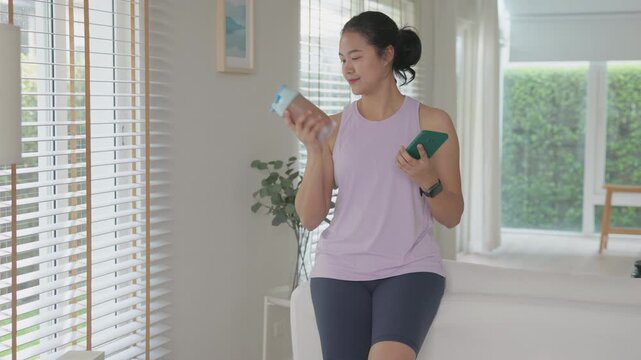 Young gen z active woman drink whey creatine shake bottle eating diet food using phone calorie plan app after home sport workout. health care asia people happy relax protect aging life weight loss.