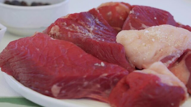 Close-up of large raw meat pieces for pilaf on a plate