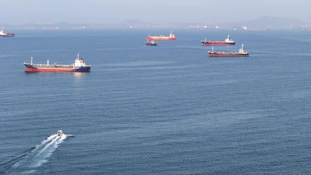 fast patrol boat LPG gas and oil tanker ships anchored in the ocean, with a fast patrol boat in the foreground. Global energy transport, war energy crisis, and Strait of Hormuz blockade
