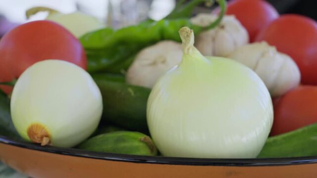 Close-up of vegetables for pilaf: onions, tomatoes, cucumbers, pepper and garlic on a plate