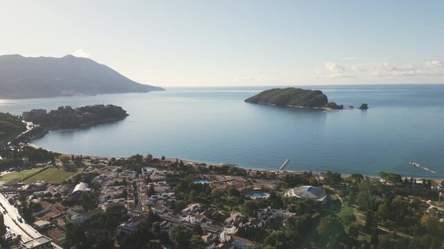 Cinematic drone pan over the coastal city of Budva and Adriatic shore on a sunny day, Montenegro.