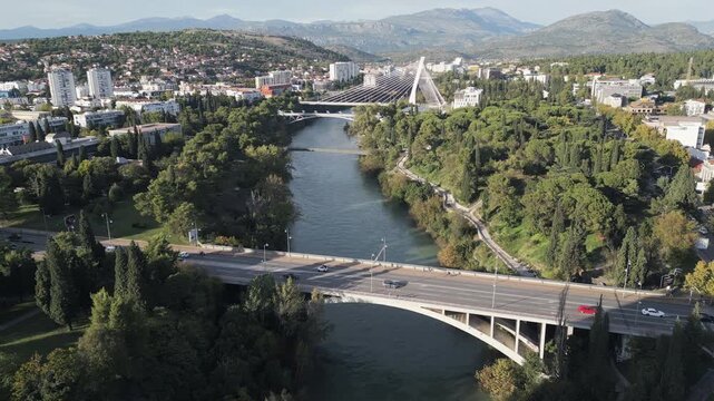 Wide drone view of Podgorica, the capital of Montenegro with lush riverbanks and a central bridge.