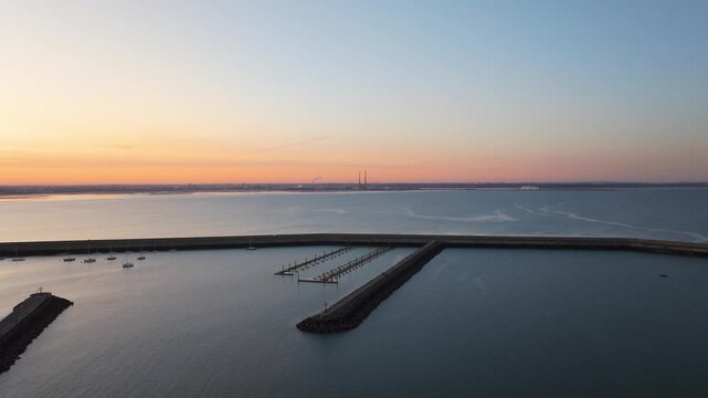 Calm waters of Dun Laoghaire Harbor with empty piers and a breakwater at sunset. Ideal for maritime or coastal development themes.