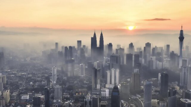 Aerial timelapse of Kuala Lumpur skyline at sunrise with low clouds and mist, Malaysia. Tilt down motion timelapse.