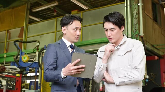 製造業の工場でタブレットを持つ作業員と信金などの打ち合わせをする営業ビジネスマンの2人　設備投資で業務効率などの借り入れのイメージ動画