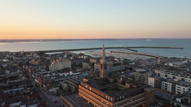 St. Michael's Church rises prominently over Dun Laoghaire, with the harbor and distant horizon bathed in warm morning light. Ideal for travel and architecture features.