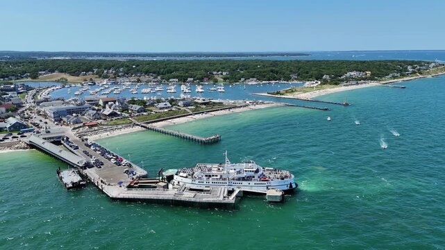 Aerial drone view of Martha&rsquo;s Vineyard harbor in Dukes County, Massachusetts, with ferry docked at pier, turquoise ocean water, marina with boats and scenic coastal town on sunny summer day.