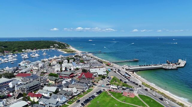 Aerial drone view of Martha&rsquo;s Vineyard in Dukes County, Massachusetts, showing coastal town, harbor, pier and turquoise Atlantic waters with boats and scenic shoreline on bright summer day. Flyover.