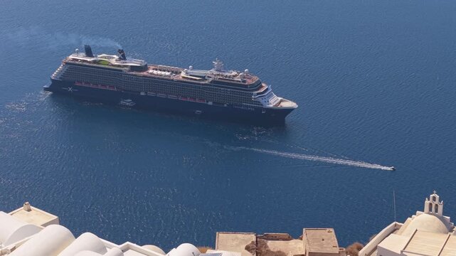 Drone footage of a cruise ship in Santorini caldera revealing Imerovigli&rsquo;s cliffside houses, showcasing the dramatic volcanic landscape and Aegean Sea.