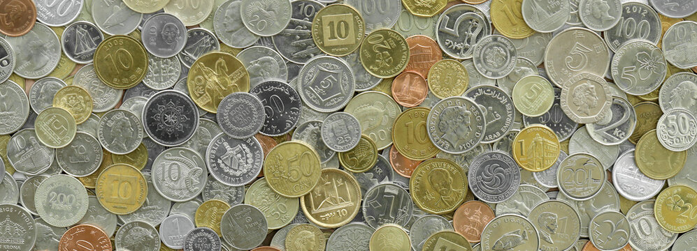 Numerous metallic coins from diverse nations piled together, top perspective