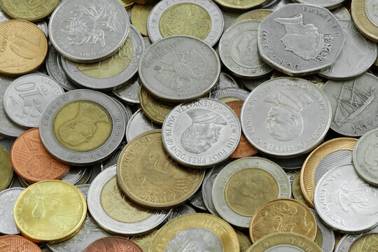 Pile of global currencies, various coin types visible up close. Different nations money together
