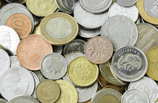 Pile of global currencies, various coin types visible up close. Different nations money together