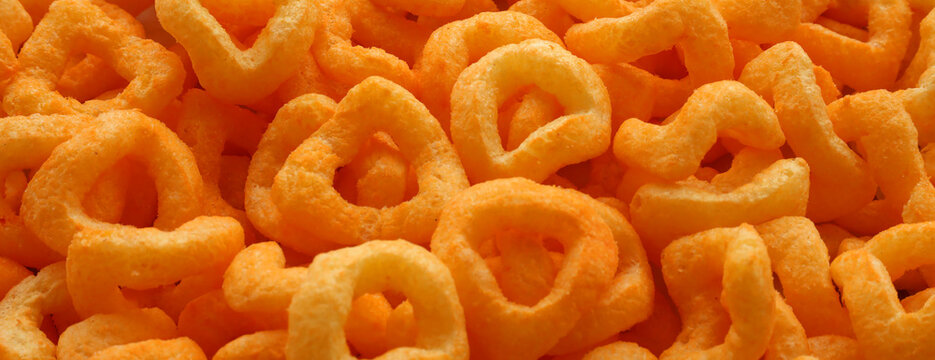 Big amount of crispy corn snacks texture surface. Orange color edible rings