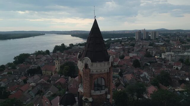 Close-up drone orbit of historic Gardos tower overlooking Danube river at dusk, Zemun, Serbia. Dramatic stormy sky.