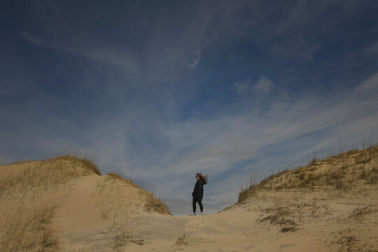 Side view teen girl standing on sand dune hair blowing Cape Hatt