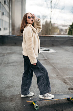 Confident young posing with skateboard on roof top