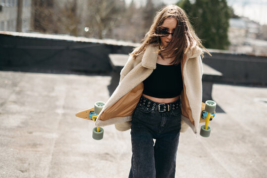 Young Woman with Skateboard on Rooftop