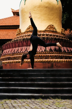 Female yogi doing handstand split on temple stairs, Bali