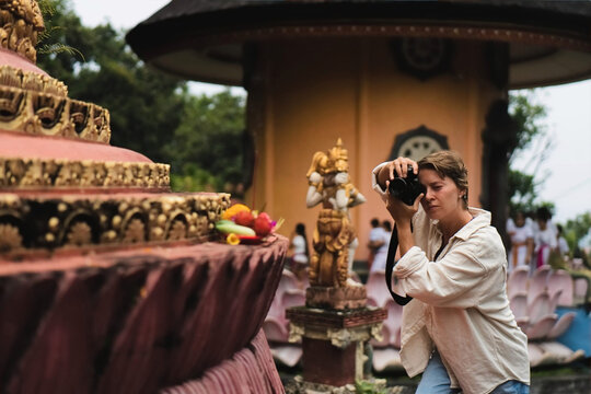 Woman tourist photographing offerings at Balinese temple ceremony