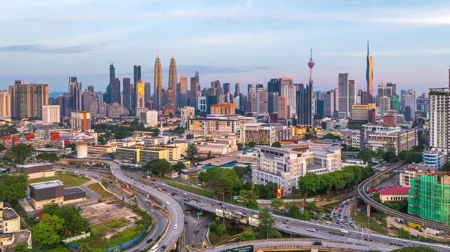 Aerial tilt-down timelapse at sunset of busy streets and roads with Kuala Lumpur skyline, Malaysia. at background.