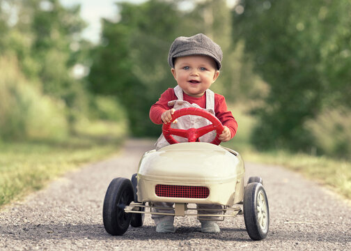 Happy Child Driving a Vintage Pedal Car on a Sunny Spring Day