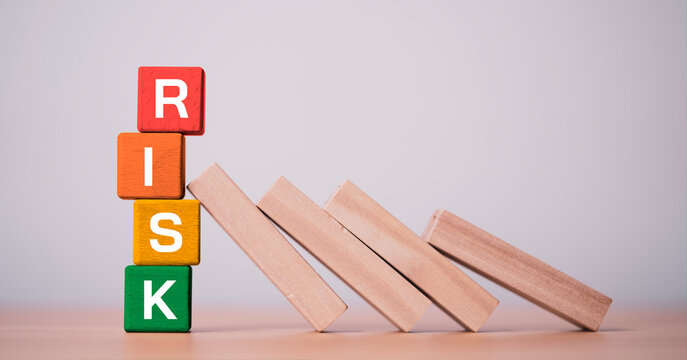 Colorful wooden blocks spelling RISK with falling domino effect symbolize business risk management, uncertainty, financial crisis, strategic planning and prevention concept.