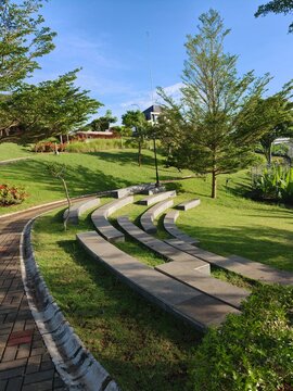 Modern stone amphitheater seating in a green public park under a blue sky