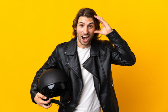 Man with a motorcycle helmet isolated on yellow background with surprise expression