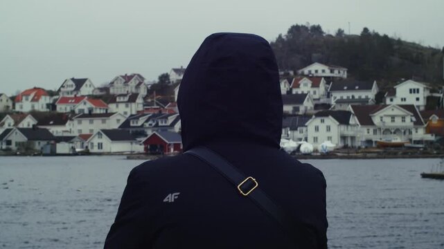 A POV shot of a lone figure in Krager&oslash;, Telemark, looking at the wooden houses of &Oslash;ya on a cloudy day in southeastern Norway