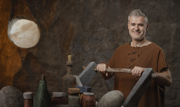 Funny Prehistoric Shopping Concept with Caveman Pushing a Stone Cart in a Cave