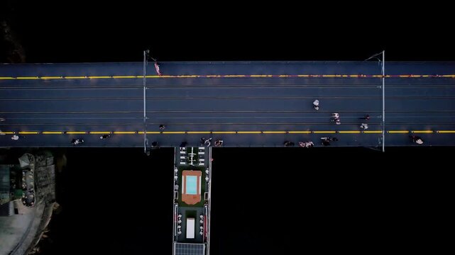 Dom Lu&iacute;s I Bridge spanning the Douro River in Porto with pedestrians walking and crossing Douro river while metro infrastructure is visible on the upper deck, drone ascending top down shot